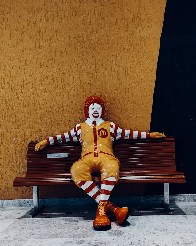 Ronald McDonald mascot sitting on a bench